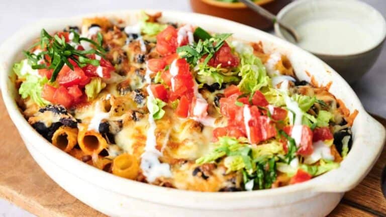 A freshly baked taco casserole garnished with lettuce, tomatoes, and green onions.