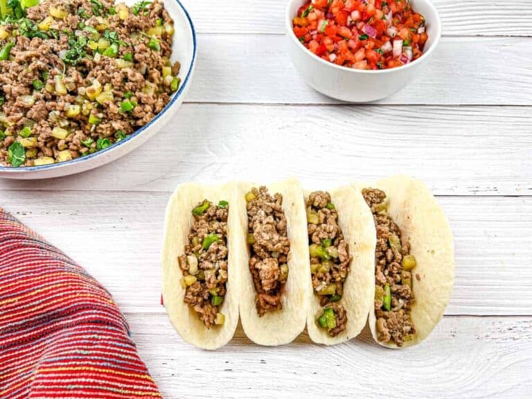 Four tacos with Mexican molida on a wooden table.