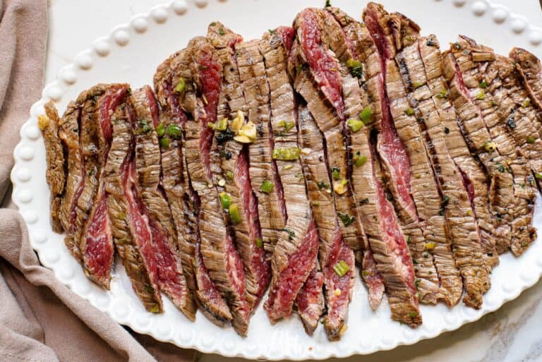 A plate of grilled steak on a white plate.