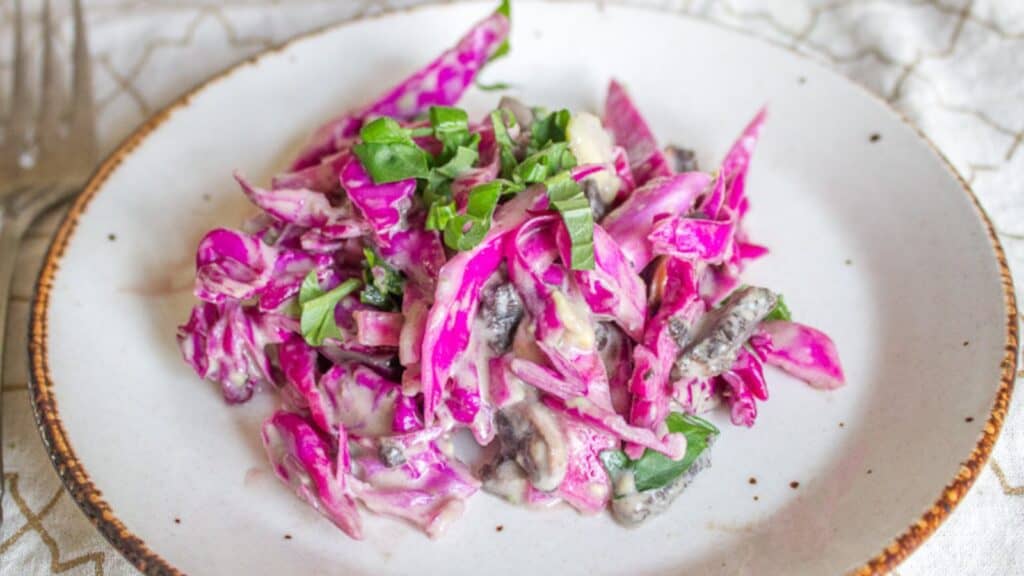 Red cabbage salad on a plate with a fork.