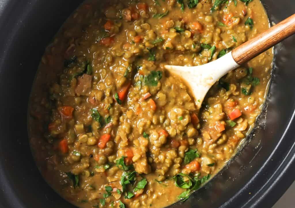 Slow cooker split pea soup in a slow cooker with a spoon.