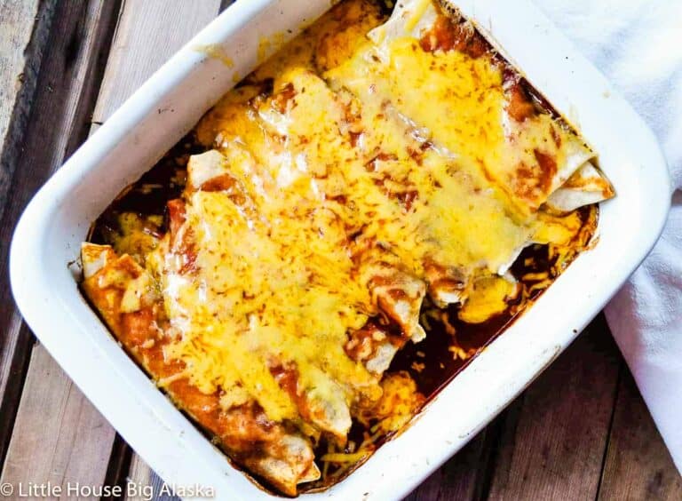 Cheesy enchiladas in a white baking dish.