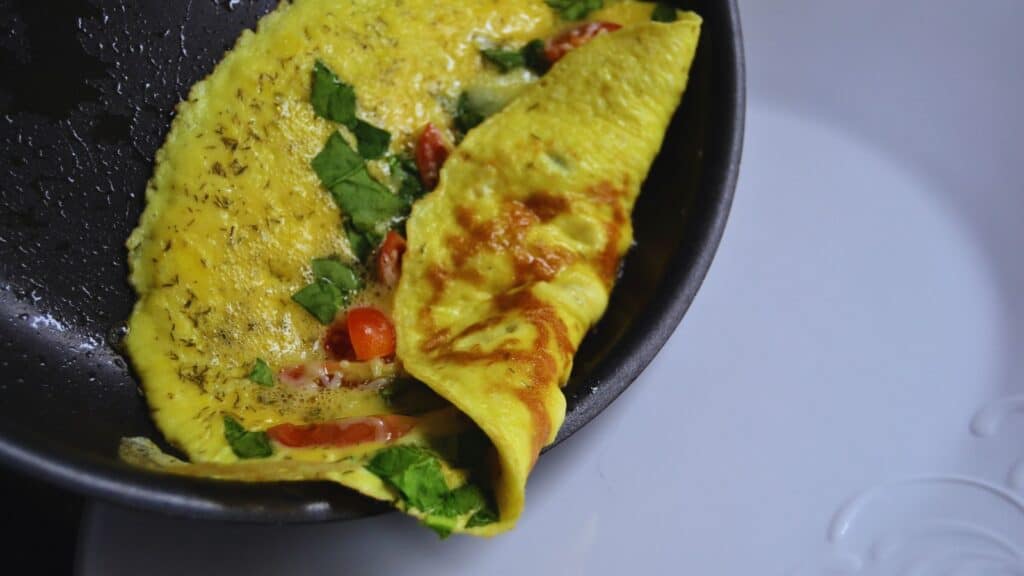 An omelet is being cooked in a frying pan.