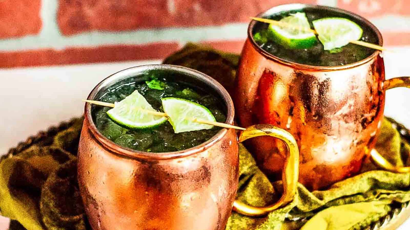 Two virgin moscow mules garnished with lime on a gold platter.
