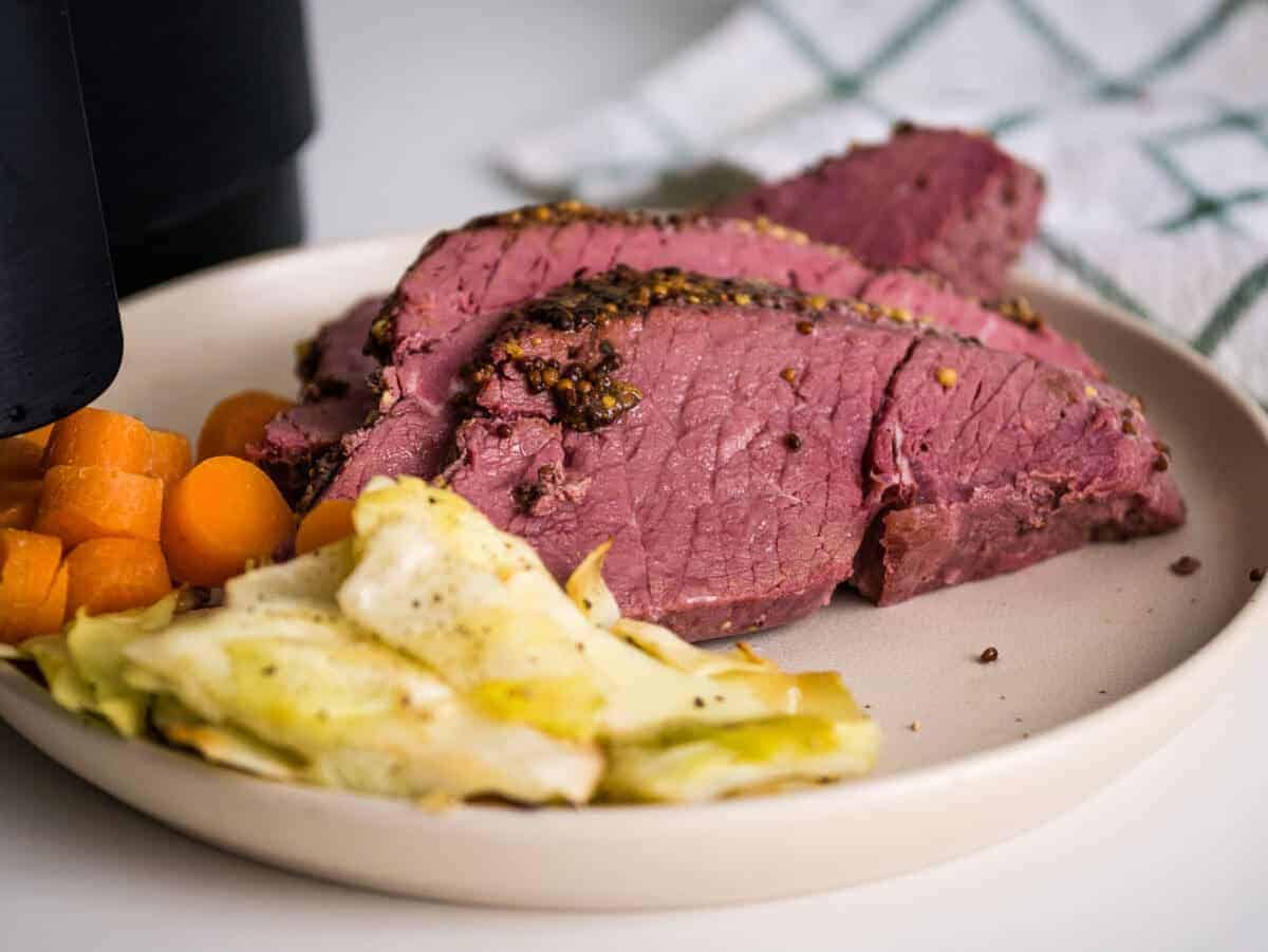 Air fryer corned beef on a plate with veggies.