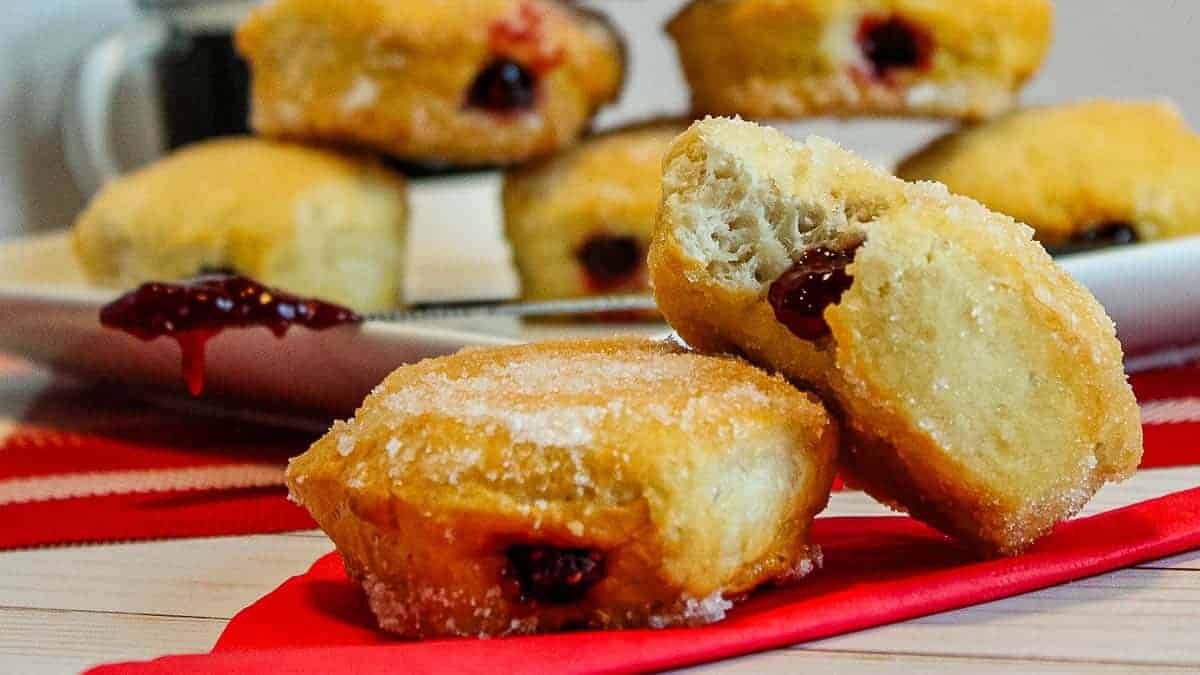 A plate of donuts on a table next to a cup of coffee.