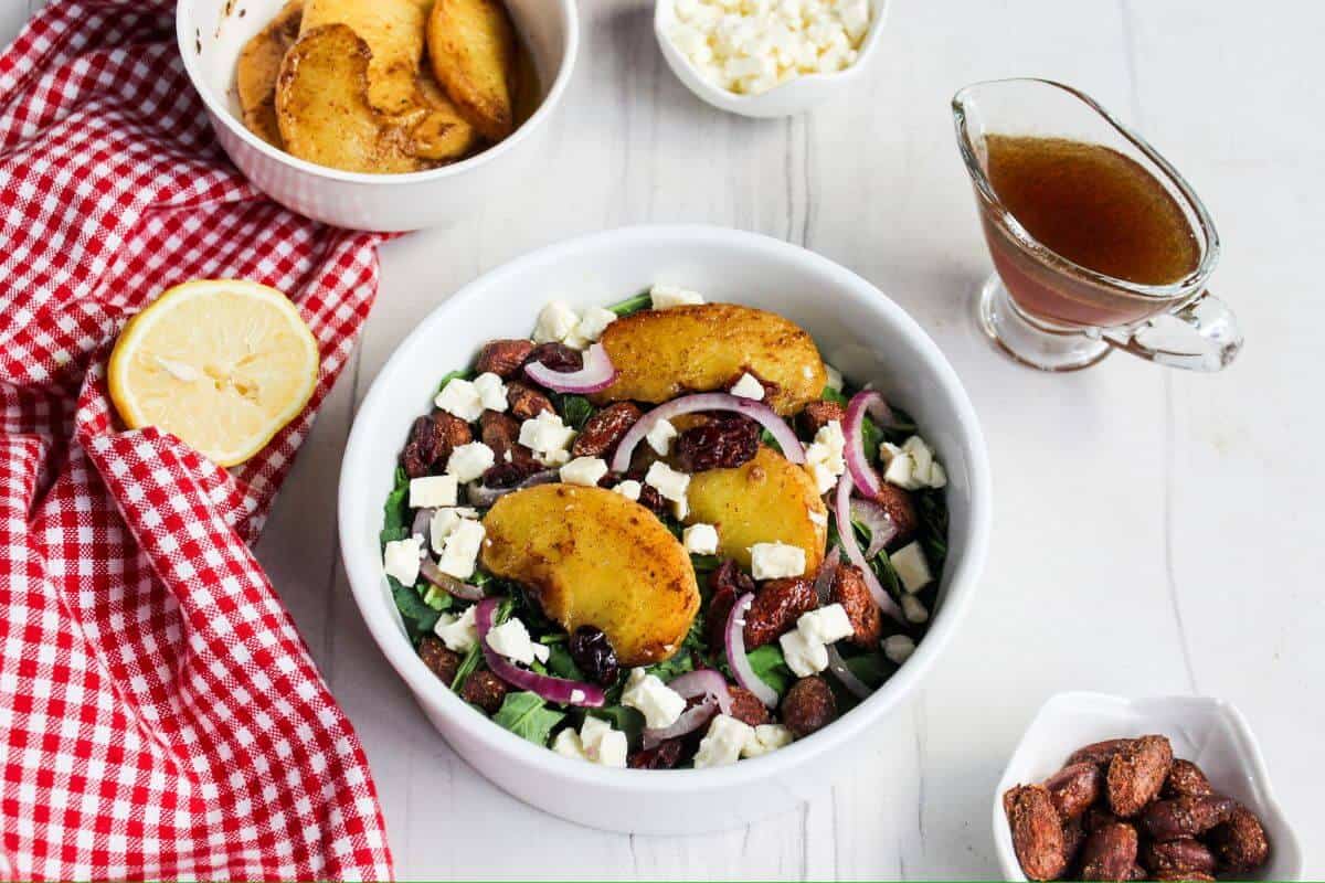 A bowl of salad with apples, cranberries, and almonds.