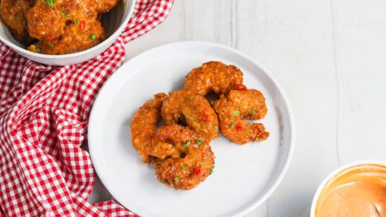 A plate of savory fritters served with a side of dipping sauce.