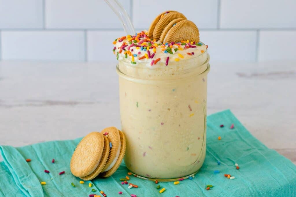A milkshake with cookies and sprinkles in a jar.