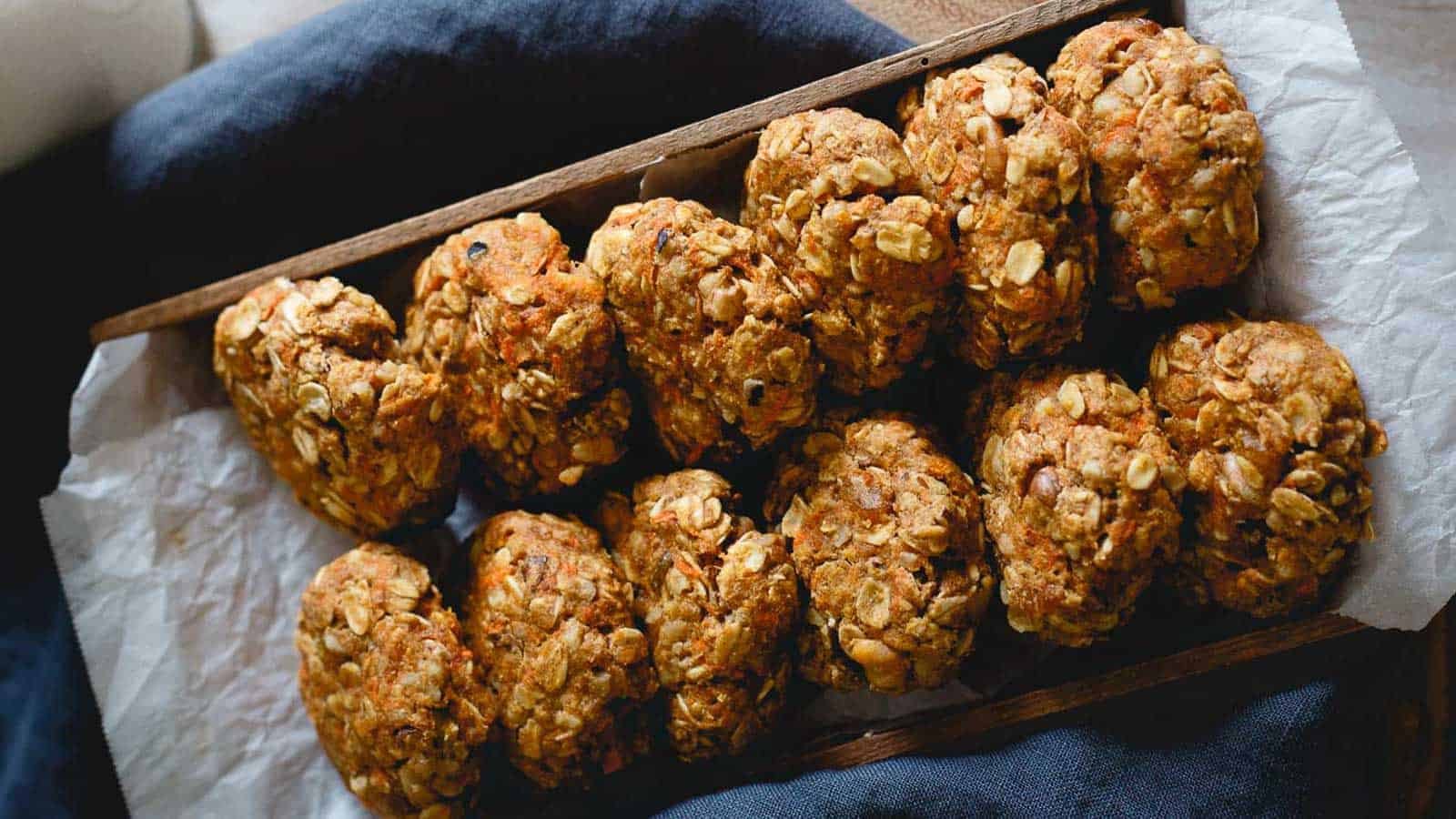 Healthy carrot cake cookies lined up in wooden box with parchment paper.