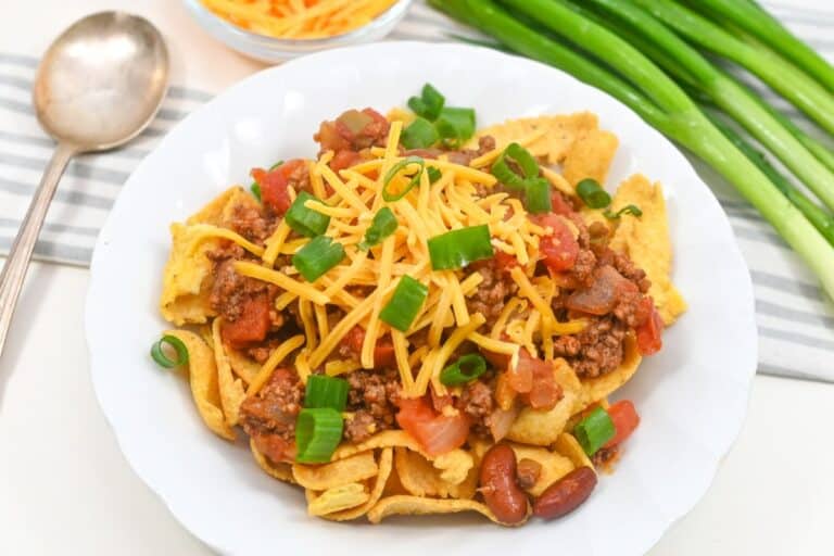 A plate of Fritos topped with ground beef, cheese, tomatoes, and green onions.