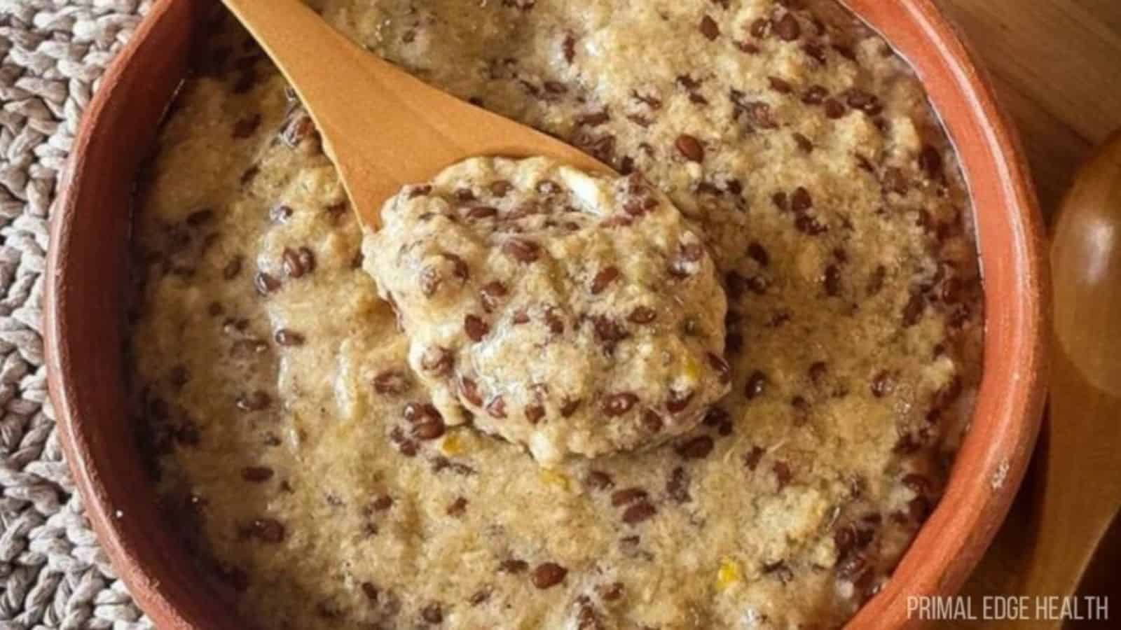 High-protein Hot Cinnamon Cereal with flax seed and coconut in red bowl with wooden spoon.