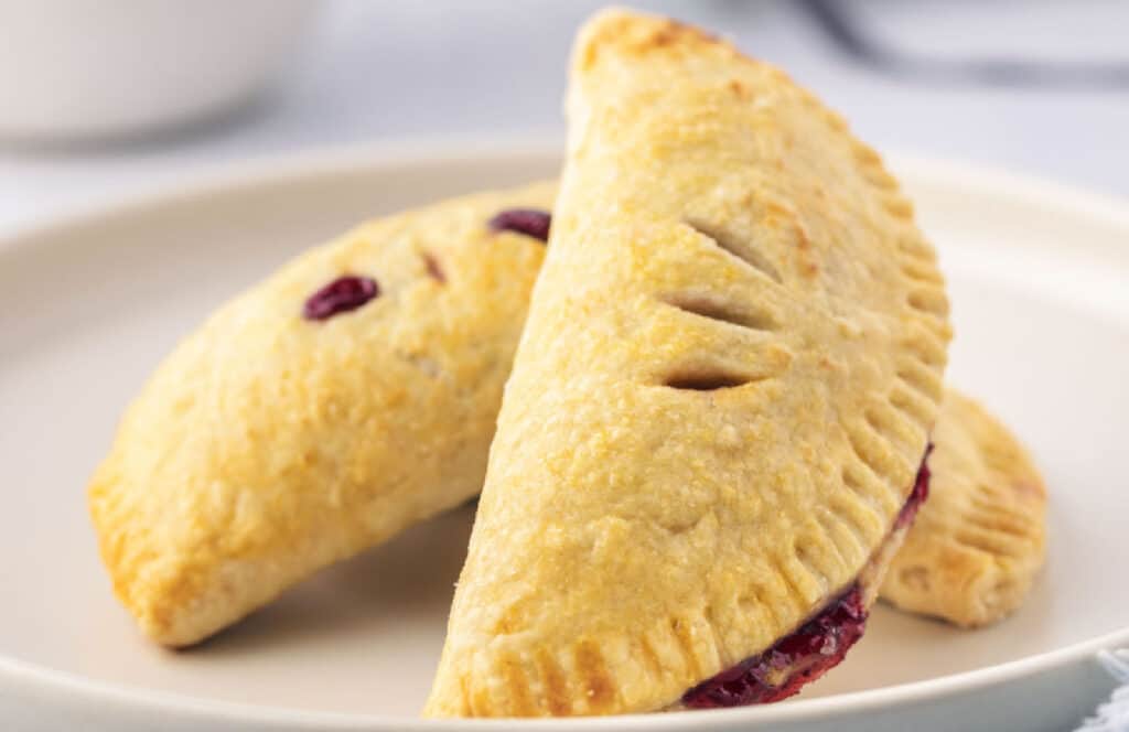 Two fruit-filled cherry handpies on a plate.