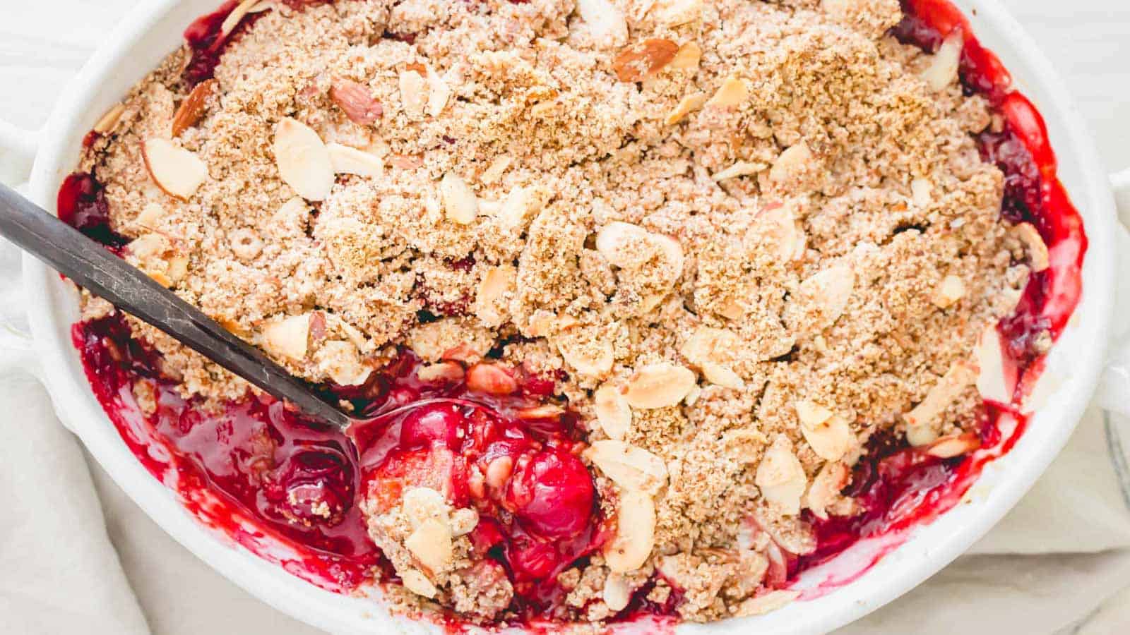 Sour cherry crisp in a baking dish with a spoon.