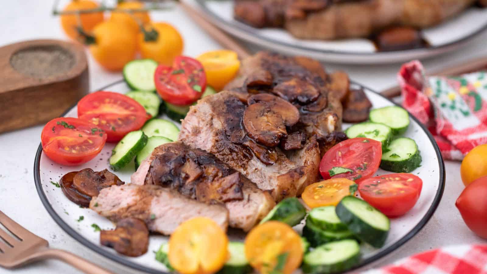 A plate with steak, tomatoes and cucumbers on it.