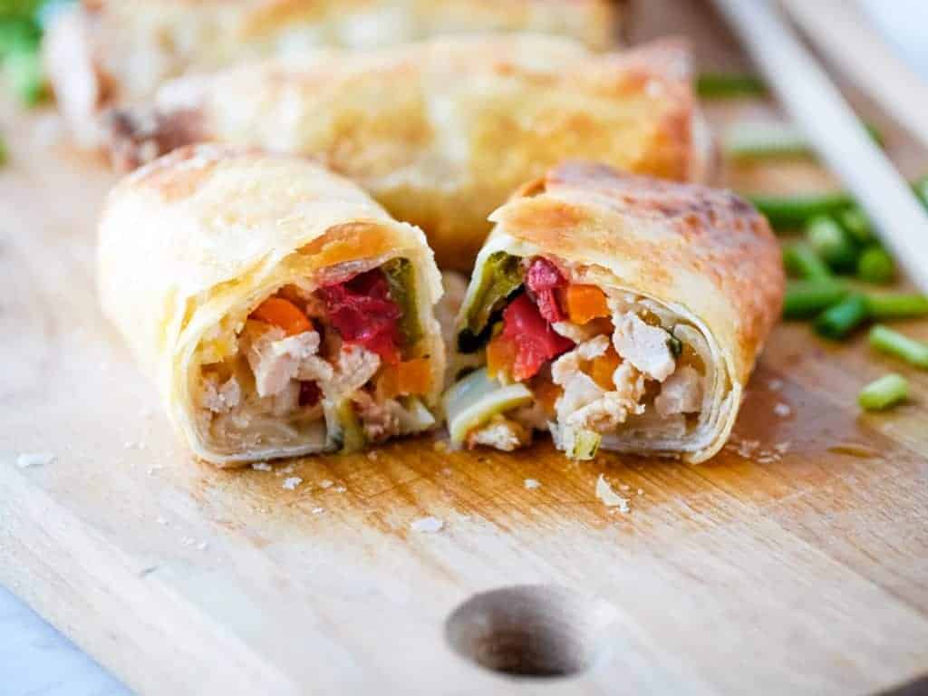 Chinese chicken egg rolls on a cutting board.