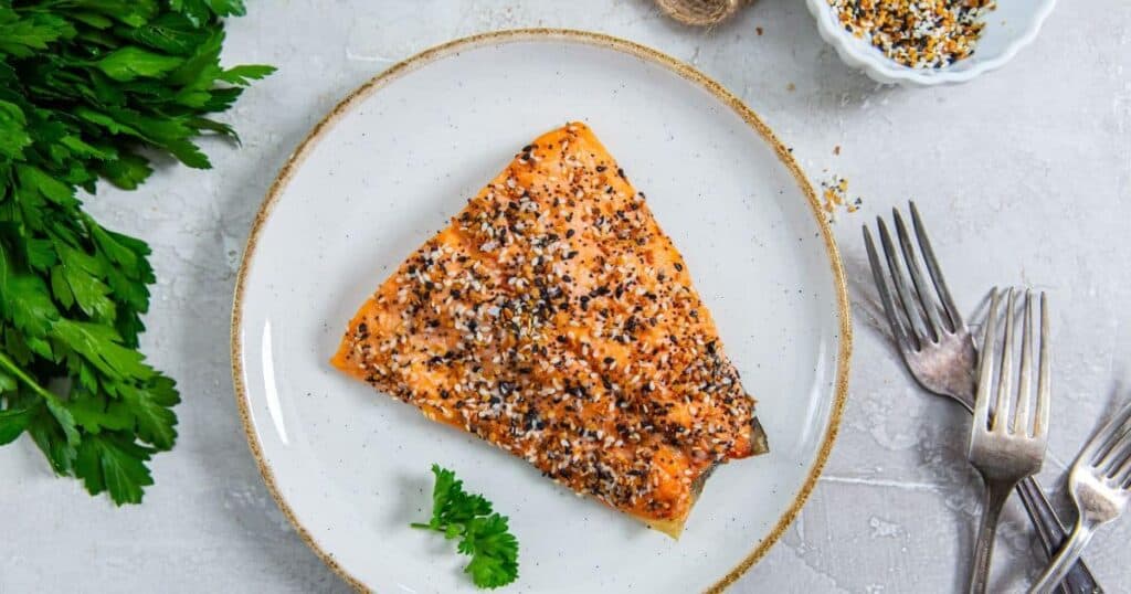 A piece of salmon with sesame seeds on a plate.