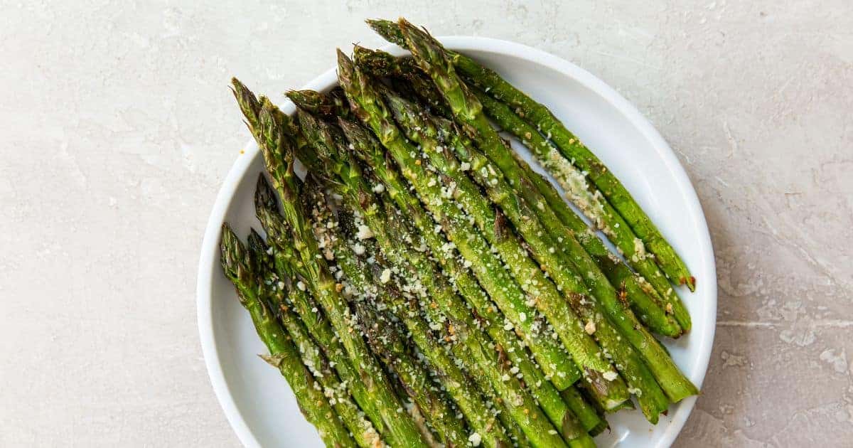 Air Fryer Parmesan Asparagus (Keto & Gluten Free) on a white plate with parmesan cheese.