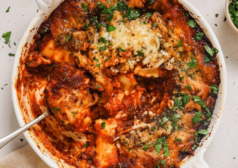 A baked cheese and tomato dish in a white casserole, garnished with herbs.