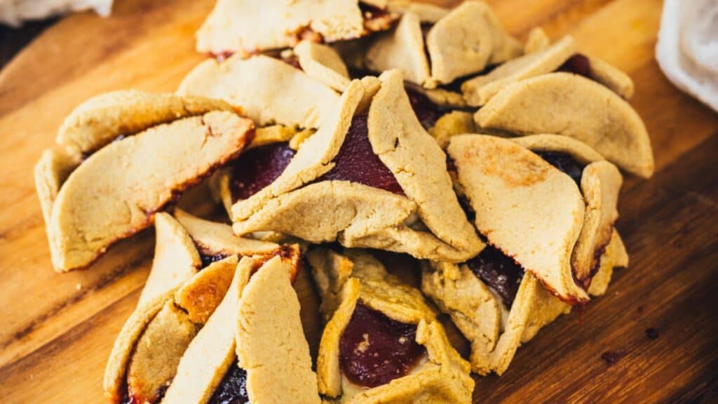 A pile of freshly baked hamantaschen cookies from vintage recipes on a wooden board.