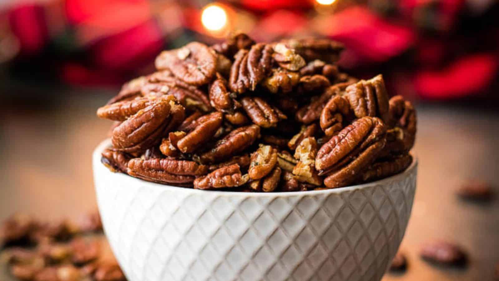 Three bowls of brown butter roasted pecans on a gray background next to a red tartan cloth.