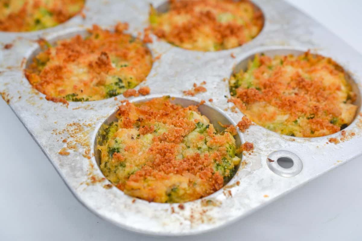 Baked broccoli and cheese muffins in a muffin tray.