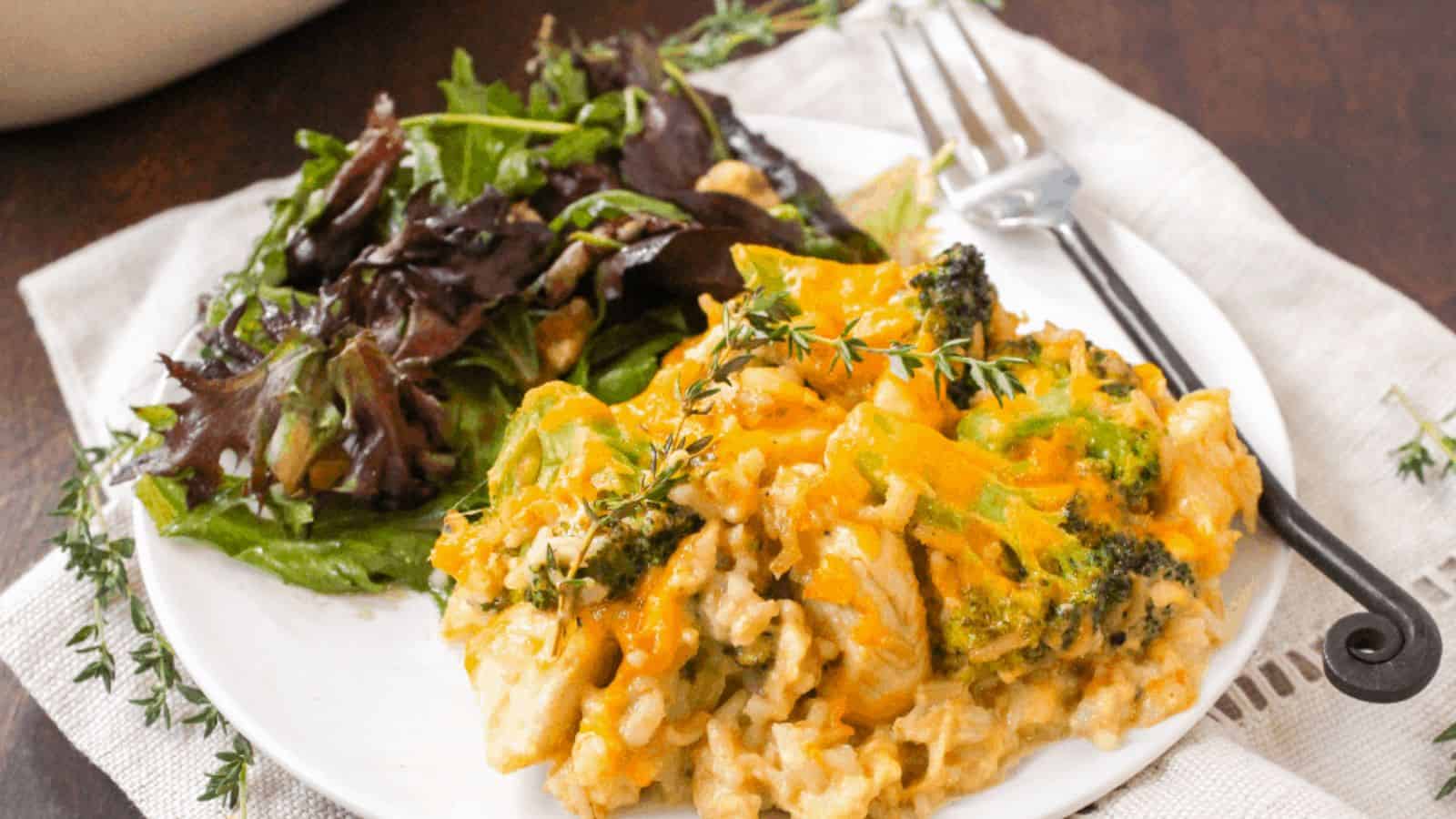 Chicken broccoli casserole on a white plate next to a green side salad.