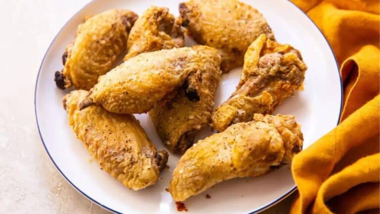 Crispy air fryer chicken wings with baking powder on a white plate.