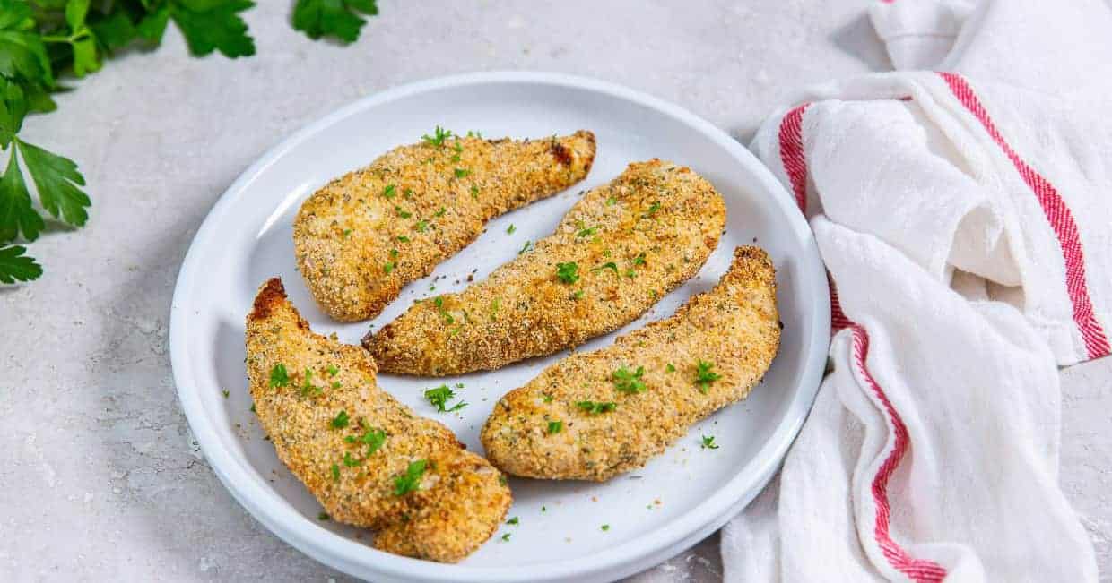 Easy Air Fryer Breaded Chicken Tenders on a white plate with parsley.