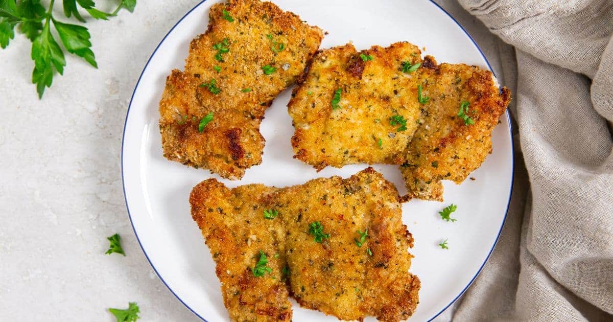 Easy Air Fryer Breaded Chicken Thighs on a white plate with parsley.