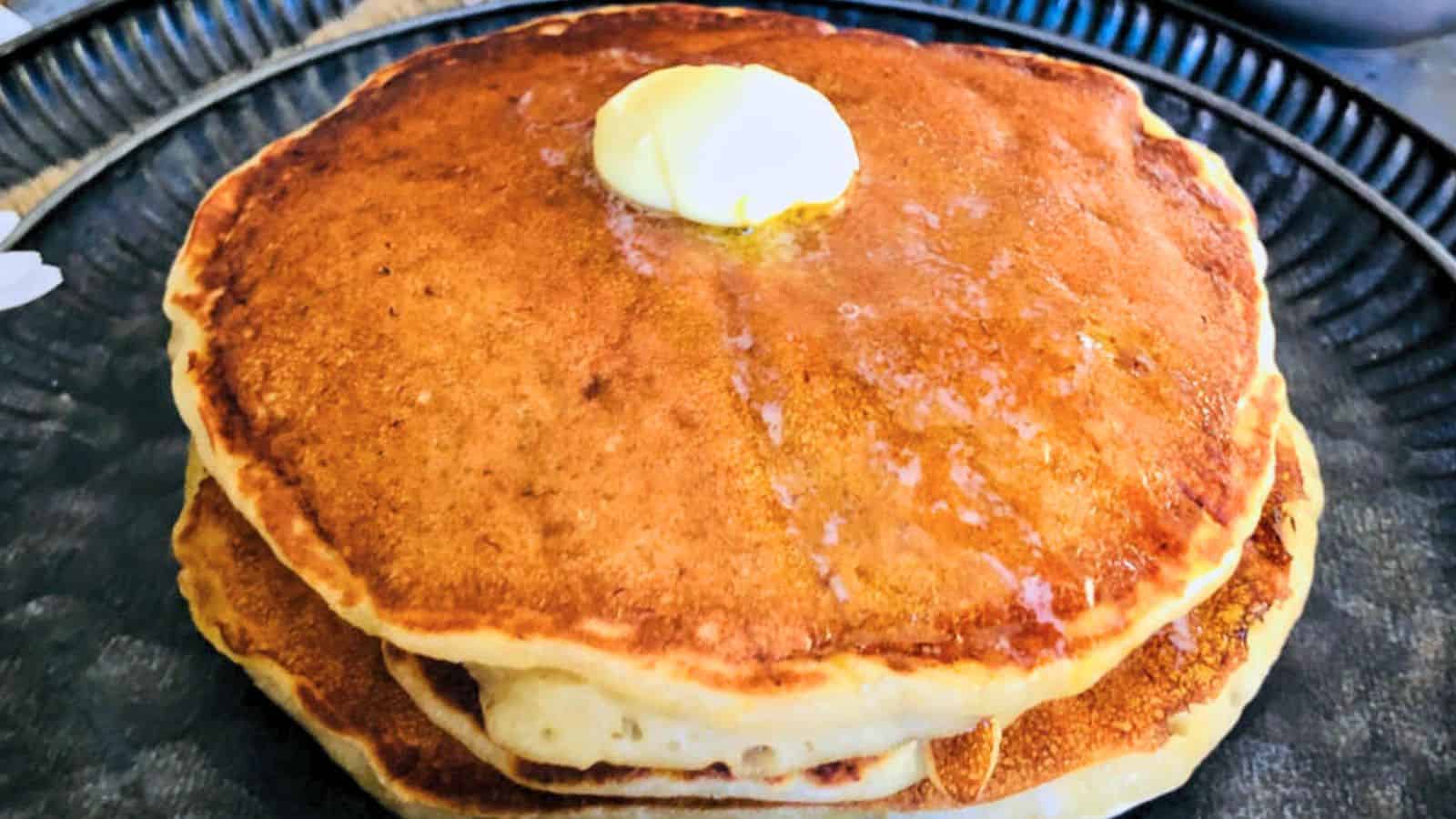 Stack of bananapancakes with a pat of butter on top, served on a plate.