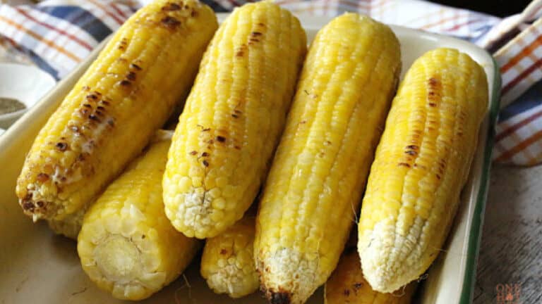 Grilled corn on the cob on a serving plate.