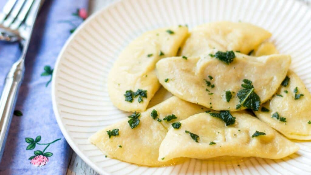 Plate of stuffed pasta with a herb garnish.