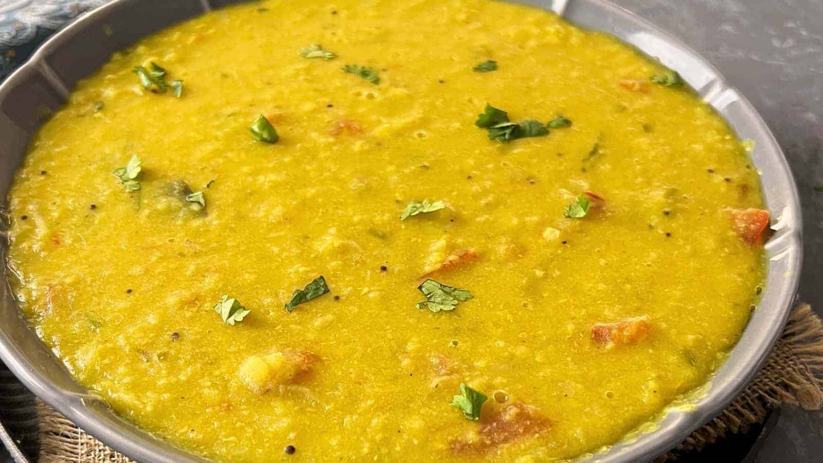 A bowl of Instant Pot Cabbage Dal garnished with cilantro on a textured surface.