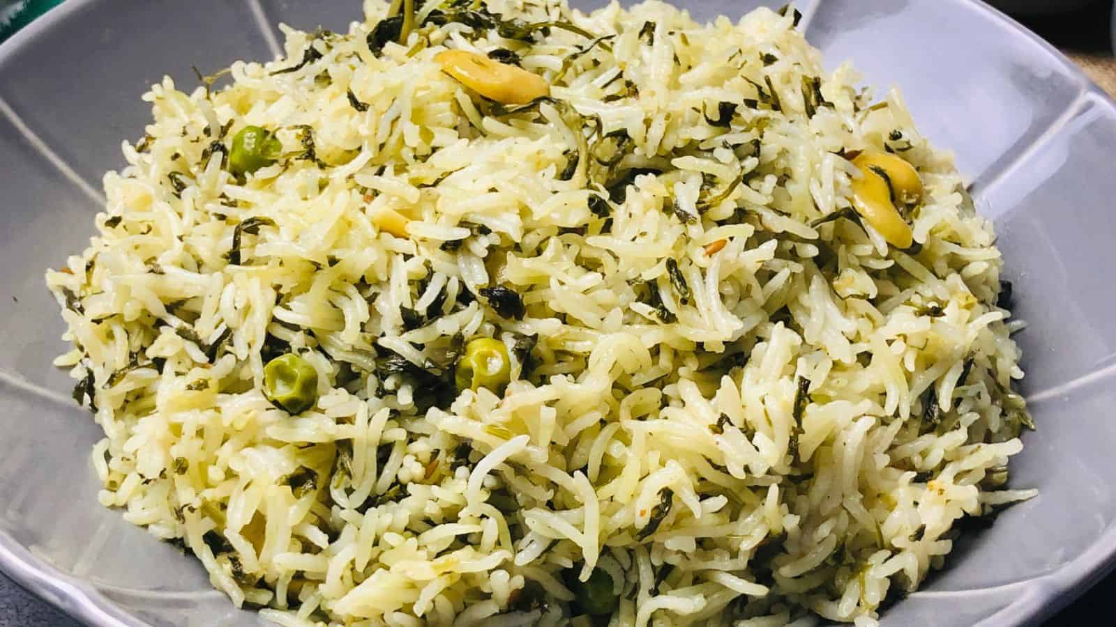 A bowl of cooked rice mixed with green peas, spinach, and seeds.