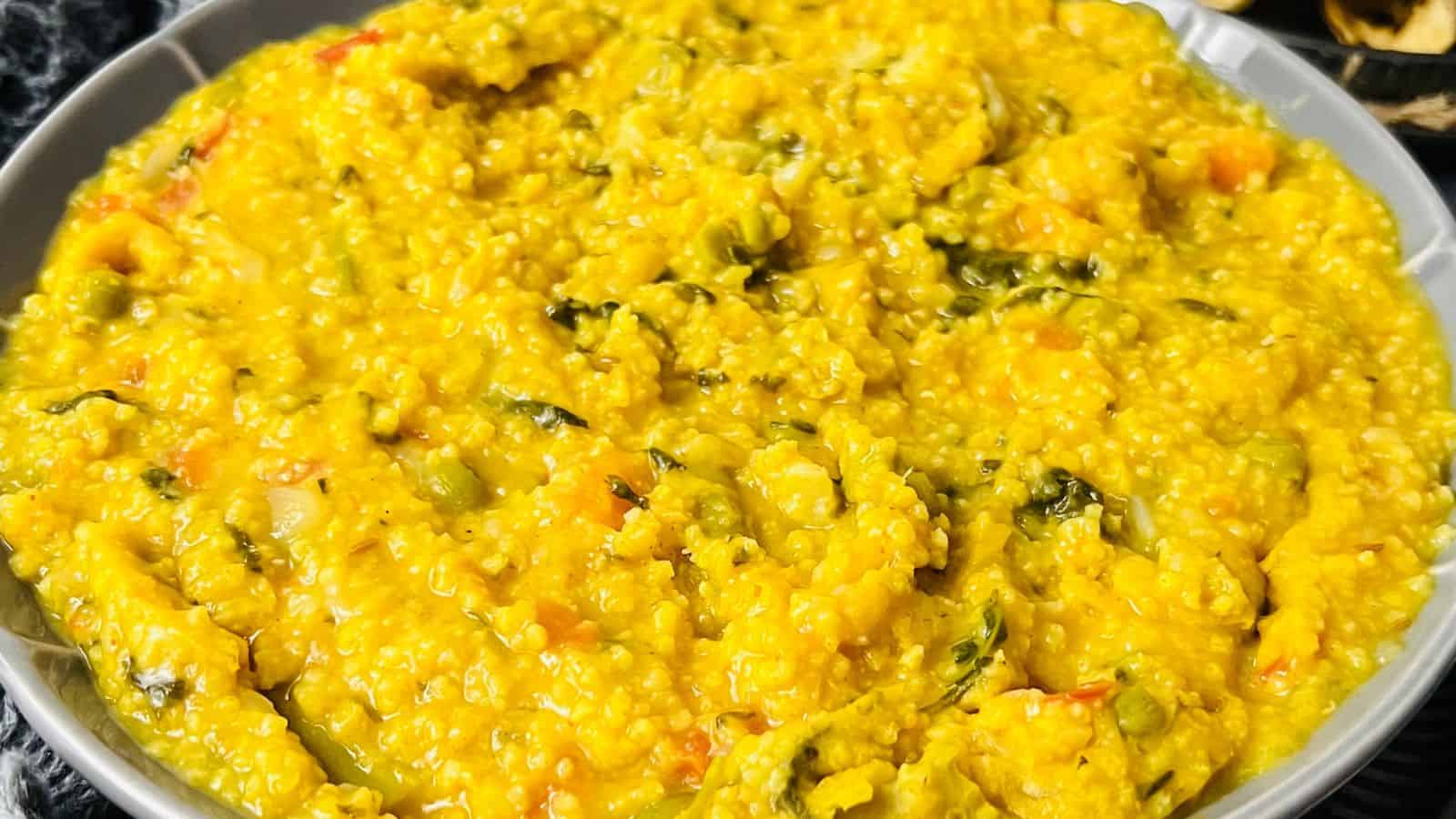 A close-up image of a bowl of khichdi, a traditional indian dish made of rice and lentils mixed with vegetables and spices.