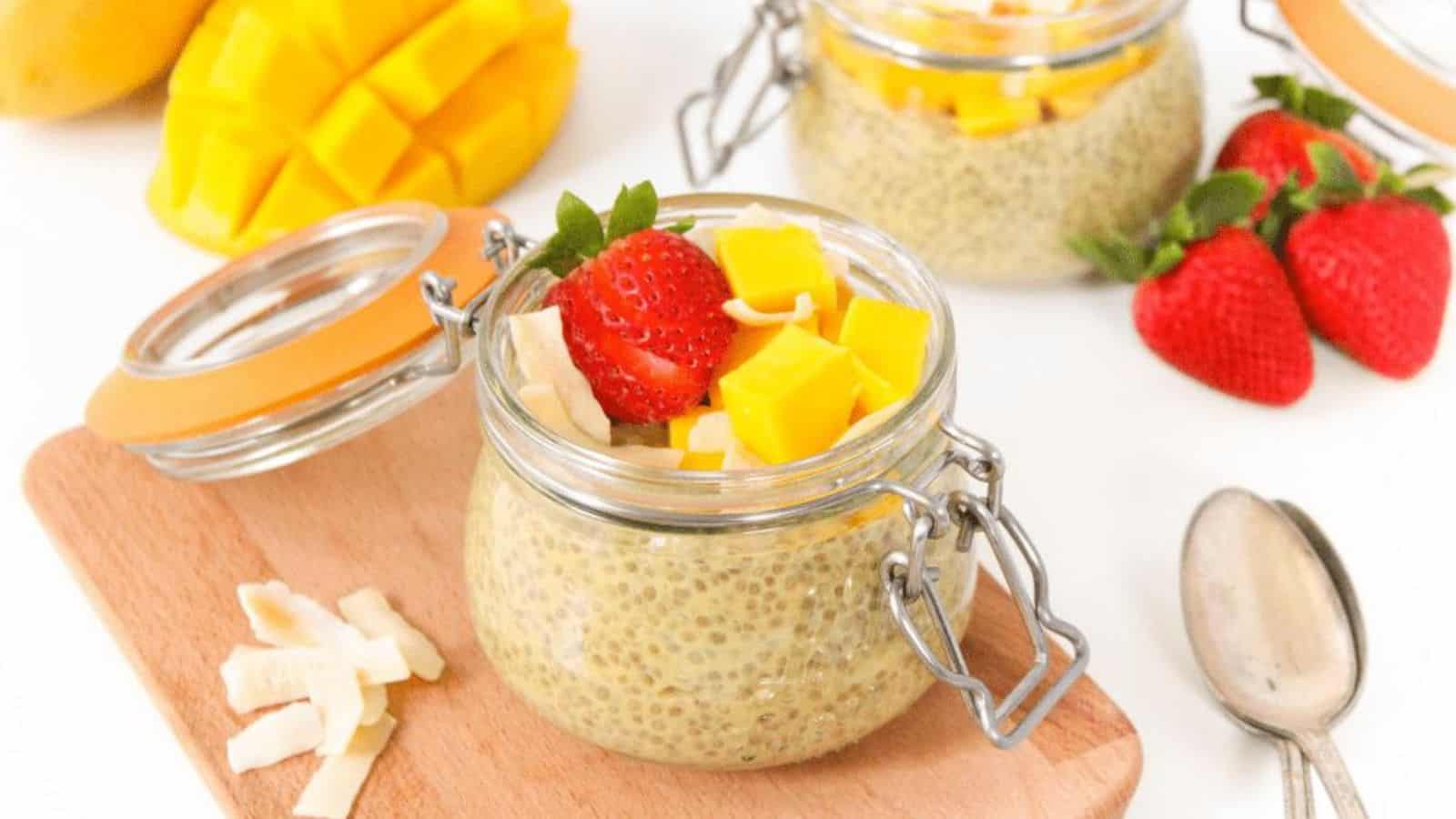 A small glass jar with chia pudding topped with mango, strawberries, and coconut flakes.