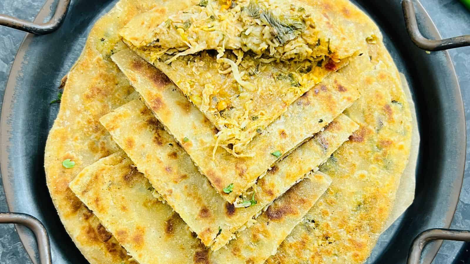 Close-up of stuffed parathas on a stovetop, filled with spiced vegetables, garnished with cilantro, cooked to a golden crisp.