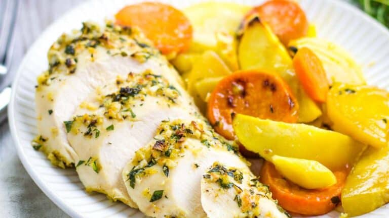 Herb-marinated baked chicken breasts served with roasted carrots and bell peppers.