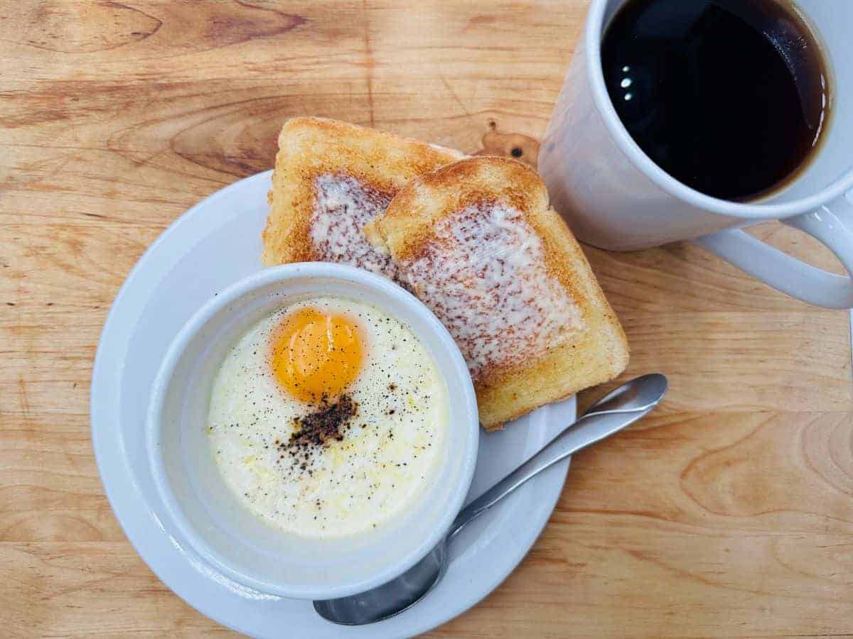 A cup of coffee and an egg on a plate.