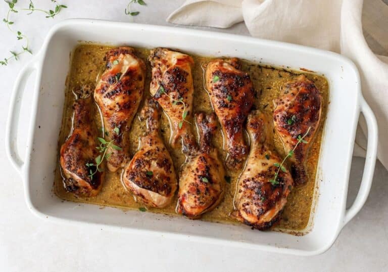 Roasted chicken breasts garnished with fresh thyme in a baking dish.