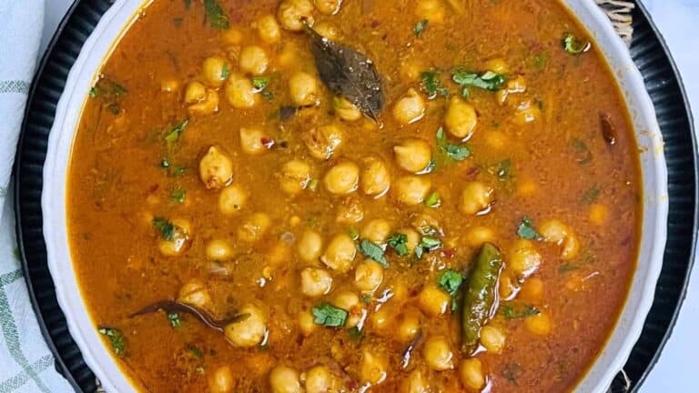 A top view of a bowl of South Indian Chana Masala with cilantro and green chilies.