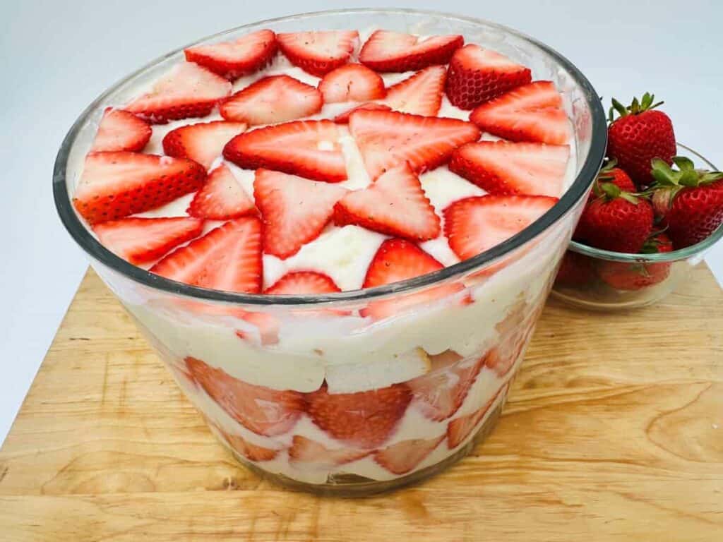 Strawberry trifle in a glass bowl with layers of custard, cake, and fresh strawberries.