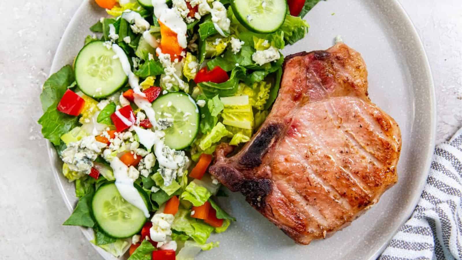 Traeger Smoked Pork Chop with a salad on a light gray plate