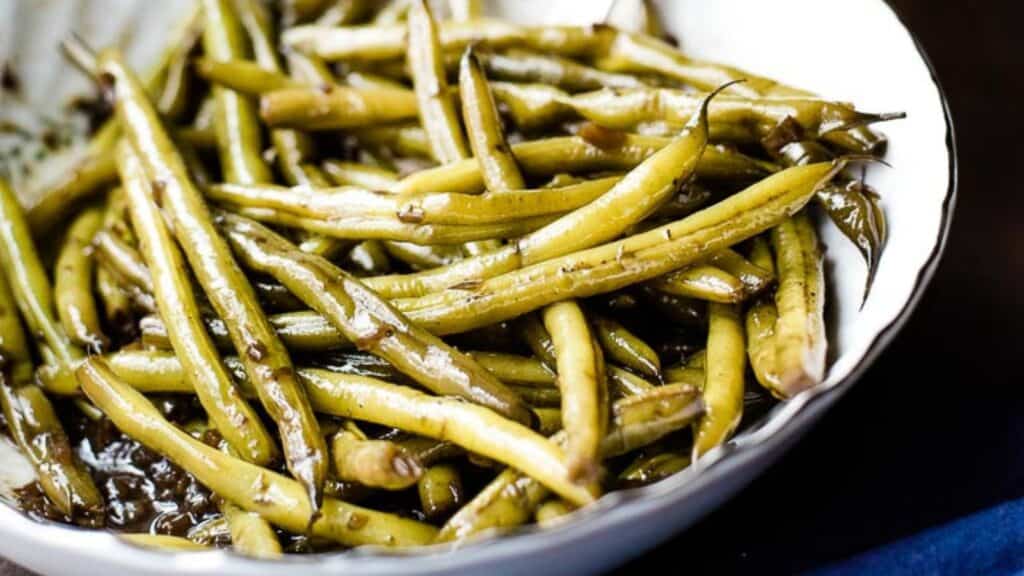A bowl of cooked green beans seasoned with herbs.