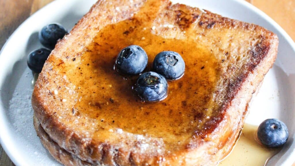 A slice of french toast topped with blueberries and syrup.