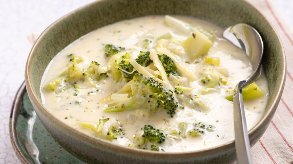Bowl of creamy broccoli soup with chunks of broccoli, served with a spoon.