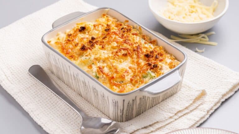 A casserole dish with cheese and broccoli on a napkin.