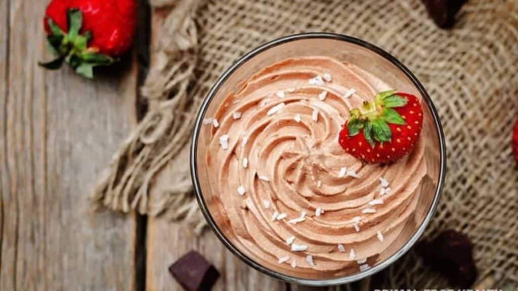 Glass bowl of chocolate mousse topped with a fresh strawberry.