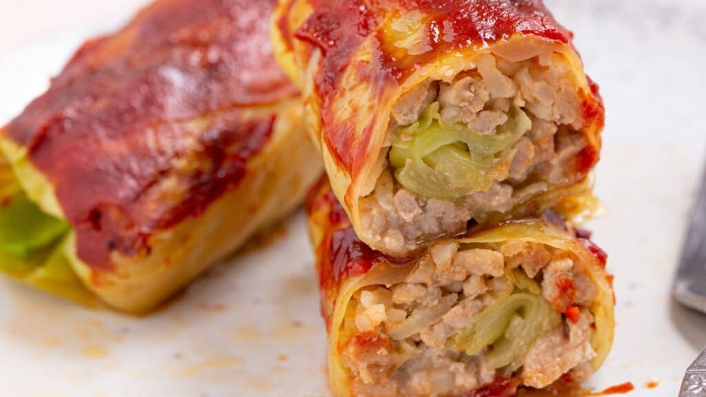 A close-up of a stuffed cabbage roll sliced in half, revealing its meat and rice filling.